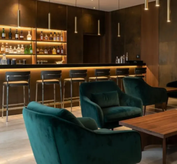 Luksusowe wnętrza lounge z ciemnymi kolorami, aksamitnymi fotelami i designerskim oświetleniem.